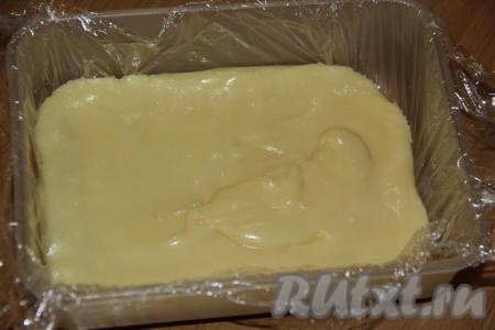 Пластиковый контейнер застелить пищевой плёнкой. Выложить массу в контейнер и разровнять.