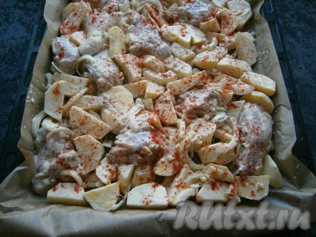 Противень застелить пергаментом, выложить на него курицу с соусом и луком, добавить картофель, перемешать прямо на противне и разровнять. Полить все растительным маслом, сверху посыпать паприкой.