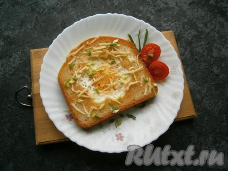 Яичницу, приготовленную в хлебе, переложить со сковороды на тарелку, посолить и поперчить, посыпать натертым сыром и измельченным зеленым лучком.&nbsp;