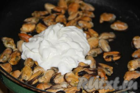 Чеснок очистить, пропустить через пресс, соединить со сметаной, хорошо перемешать. Когда мидии протушатся минут 15, выложить на сковороду смесь сметаны и чеснока, перемешать и томить на медленном огне, примерно, 5-7 минут.&nbsp;