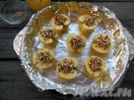 Поверх меда выложите порубленные грецкие орешки. Форму с яблоками отправьте в заранее разогретую духовку.