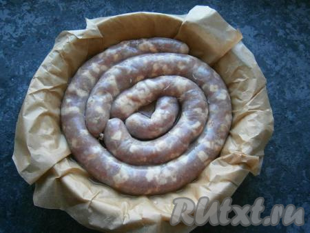 Любую подходящую по размеру форму для запекания застелить пергаментом и выложить домашнюю свиную колбасу в один слой. Влить в форму 50-70 мл воды.