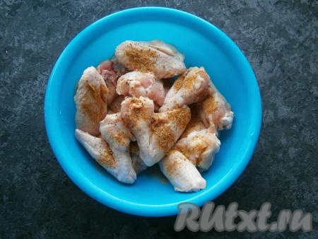 Немного крылья посолить, посыпать специями, перемешать.