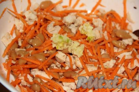 Затем к курице и моркови добавить консервированную белую фасоль (без жидкости) и пропущенный через пресс чеснок, перемешать салат.