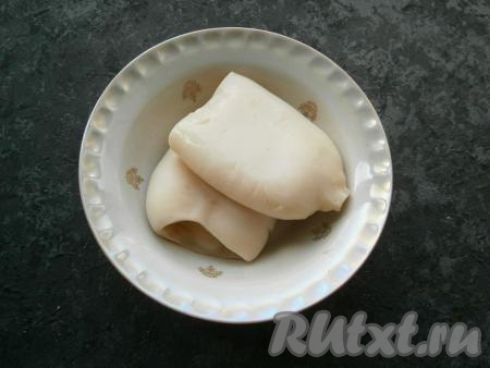 Тушки кальмаров вымыть, поместить в кастрюлю, залить холодной водой, поставить на огонь. Когда вода закипит, снять с огня кастрюлю, накрыть крышкой и оставить кальмаров в воде на 3-4 минуты. Затем достать кальмаров из воды, залить холодной водой, снять кожицу и дать полностью остыть.