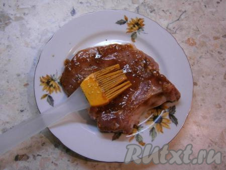 Каждый стейк из свинины обильно смазать с двух сторон подготовленным соусом-маринадом.