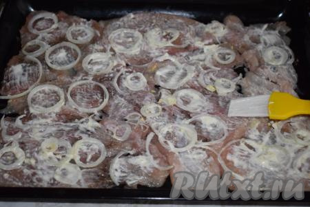 Далее куриные отбивные с луком при помощи кулинарной кисти смазываем майонезом.