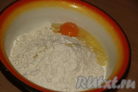 В получившуюся мучную смесь добавить яйцо, влить минералку и растительное масло, вначале вилкой, а затем руками замесить тесто.