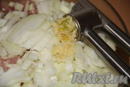 Пропустить очищенный чеснок через пресс и выложить к фаршу с луком.