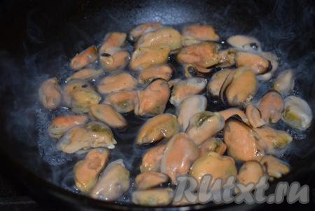 Теперь приготовим мидии для нашего салата. Слегка размороженные мидии отправляем на разогретую сухую сковороду. Мидии начнут активно размораживаться, выделяя жидкость, обжариваем их на среднем огне, периодически помешивая, до того момента, когда в сковороде останется совсем немного жидкости.