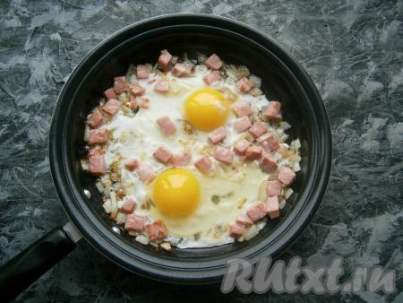 Обжаривать лук с колбасой на среднем огне, перемешивая, до румяности колбаски. Далее аккуратно вбить яйца.