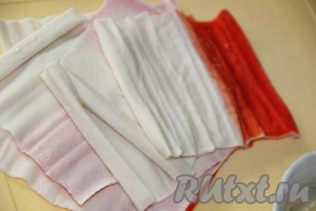 Крабовые палочки (у меня охлаждённые) аккуратно развернуть. Если вы для этой закуски купили замороженные крабовые палочки, тогда заранее разморозьте их при комнатной температуре, а затем разверните.