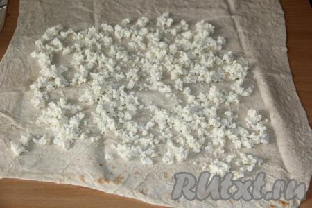 На лист лаваша выложить творог и разровнять, оставляя края чистыми.