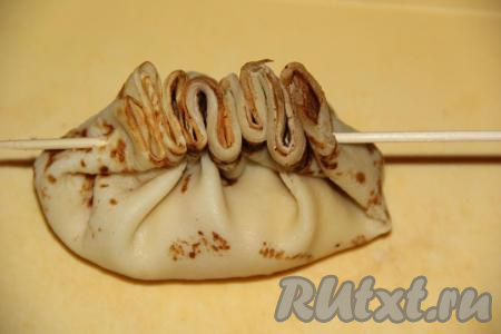 Сложить блинчик пополам и совместить края. Собрать края в гармошку и проколоть деревянной шпажкой (как на фото).