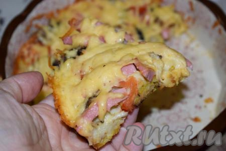 Готовую пиццу на батоне достаем из духовки, даем немного остыть и нарезаем на порционные кусочки. На фото видно, что кусочки пиццы не разваливаются, начинка хорошо держится на основе, есть такую пиццу удобно.