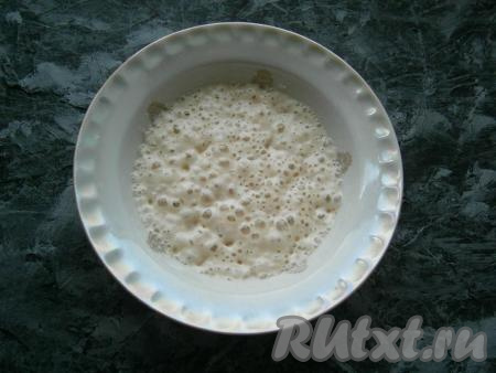 В теплую воду всыпать сухие дрожжи, 1 чайную ложку сахара и 1 столовую ложку муки от общего количества, перемешать и оставить в теплом месте на 10 минут. Дрожжи должны оживиться, появятся характерные пузырьки.