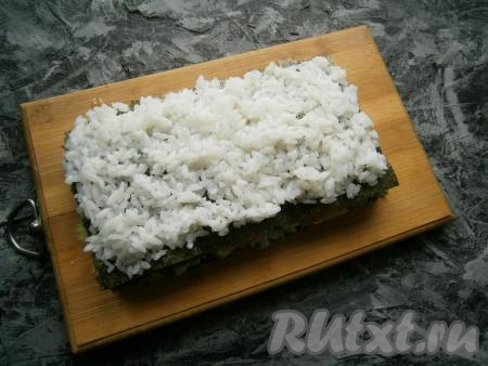 Огурцы промазать немного сыром и накрыть третьим листом нори, на котором распределить оставшийся рис, который сыром смазывать не нужно.