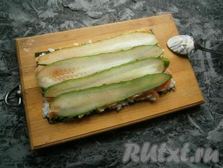 На рыбу выложить тонкие слайсы из свежего огурца, которые можно нарезать с помощью овощечистки.