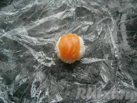 Пленку раскрутить и у вас получится довольно плотный, не рассыпающийся комок риса с рыбкой.