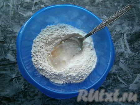 В получившейся смеси сделать углубление, затем влить растительное масло и частями вливать теплую воду, ложкой замешивая тесто.