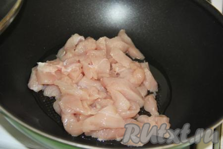 В сковороде с высокими бортиками (или в сковороде вок) разогреть растительное масло, выложить куриное филе, нарезанное на брусочки (или кубики).