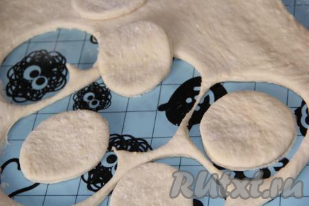 Готовое тесто хорошо обмять и дать подняться второй раз. Затем обмять тесто и раскатать его в пласт толщиной, примерно,&nbsp;1 см. Вырезать кружочки с помощью рюмки.