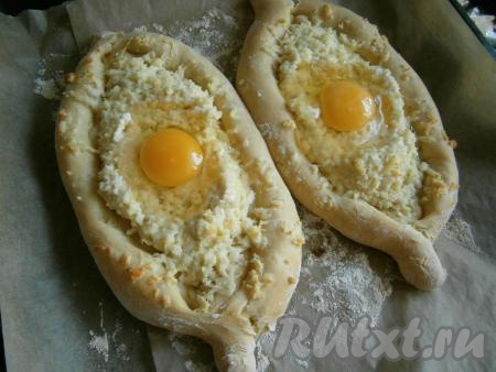 Отправить хачапури в разогретую до 180-190 градусов духовку на 25-30 минут, после чего вынуть, сделать в середине углубления и аккуратно разбить по яйцу.