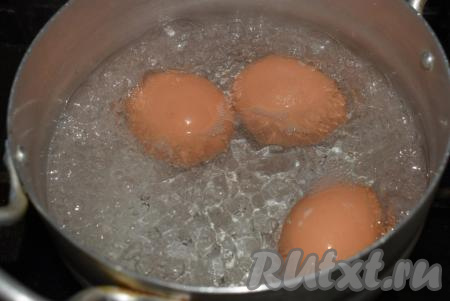Яйца кладём в отдельную кастрюлю с водой, ставим на огонь и отвариваем до готовности (в течение минут 10 с момента закипания воды на небольшом огне), затем снимаем с огня, заливаем холодной водой и остужаем.