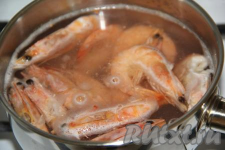 В другой кастрюле тоже вскипятить воду, выложить креветки, после закипания уменьшить огонь и варить их 2-3 минуты. Отваренные креветки откинуть на дуршлаг, остудить и очистить.