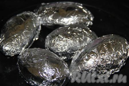 Завернуть картофелину в фольгу и выложить на противень. Аналогично полить маслом, посолить и завернуть в фольгу оставшиеся картошины. Запекать картофель в разогретой духовке 1 час при температуре 220 градусов. Готовность можно проверить зубочисткой (зубочистка будет легко входить в картошку).