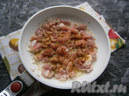 К обжаренном луку выложить кусочки курицы, поперчить, посолить, посыпать специями, перемешать.