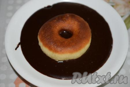 Выливаем глазурь в блюдце и опускаем в нее пончик, окуная одну сторону.