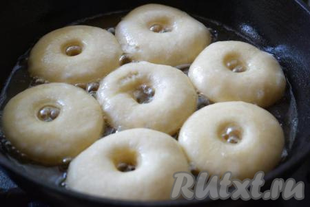 Далее в глубокую небольшого диаметра сковороду наливаем растительное масло и разогреваем его на среднем огне. В разогретое масло кладем пончики и начинаем жарить на среднем огне сначала с одной стороны до подрумянивания.