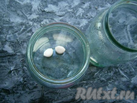 На дно хорошо вымытых литровых банок поместить по 2 очищенных зубчика чеснока.