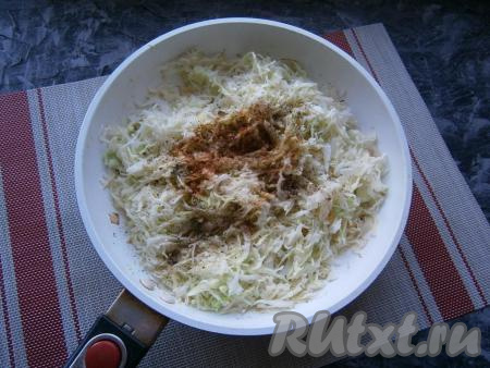 Обжарить лук, помешивая, около 3-4 минут, затем добавить в сковороду тонко нашинкованную капусту, всыпать соль, чёрный молотый перец и специи, перемешать.
