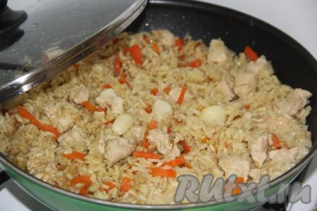 Поверх риса выложить очищенные зубчики чеснока. Накрыть сковороду крышкой.&nbsp;Как только плов с куриной грудкой закипит, убавить огонь до минимума и готовить, примерно, 25 минут. Вода полностью впитается в рис.