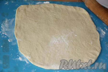 Подошедшее тесто обмять и разделить на две равные части. Припылить поверхность стола мукой и раскатать одну часть теста в круг.
