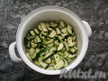 Удалить из болгарского перца семенные коробки, очистить лук и чеснок. В кастрюлю нарезать огурцы полукружочками.