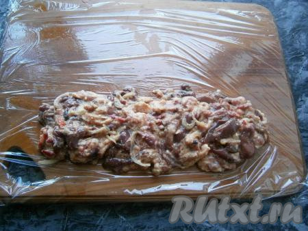 Фарш снова перемешать и оставить на 30-40 минут. Далее на лист пищевой плёнки выложить горизонтально часть фарша.