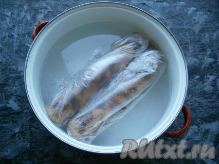 Каждую колбаску поместить дополнительно в целлофановый пакет, который плотно завязать. Также вы можете использовать и рукав для запекания, тщательно зафиксировав края. Поместить колбасу в большую кастрюлю с холодной водой.