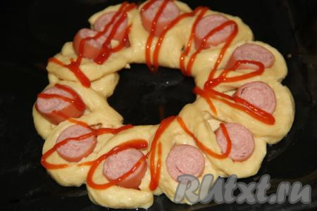 Поверх теста и сосиски нанести решётку из кетчупа. Можно смазать верх теста кетчупом с помощью кисти.&nbsp;