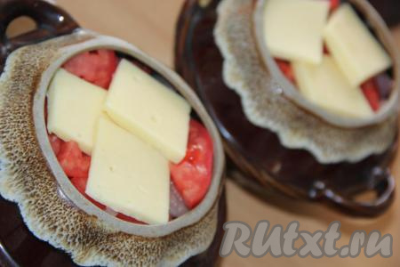 Поверх помидоров выложить пару долек сыра. Добавить в каждый горшочек по 100 мл&nbsp;воды (вместо воды можно влить мясной или овощной бульон).