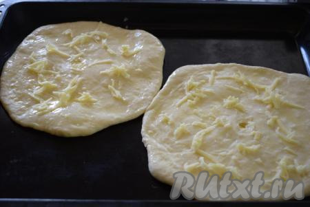 Далее смазываем наши хачапури яйцом, смешанным с молоком, и посыпаем натёртым на крупной тёрке сыром.