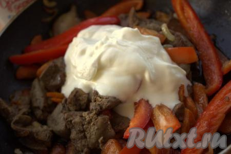 Затем к луку, моркови и куриной печени добавить нарезанный болгарский перец, 3 столовые ложки сметаны, соль, чёрный молотый перец и любимые специи, тщательно перемешать.