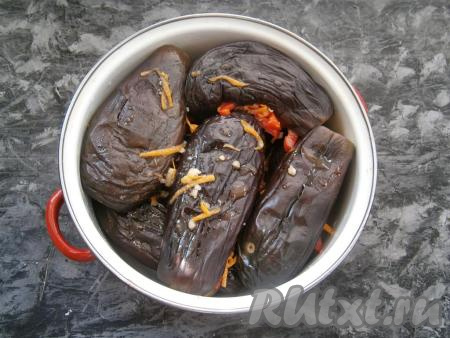 Баклажаны разрезать пополам, но не до конца (как книгу), нафаршировать их смесью моркови и перца. Баклажаны, фаршированные овощами, сложить поплотнее в два слоя в кастрюлю.