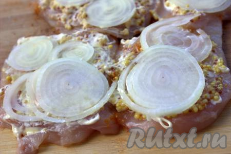 Очистить лук, нарезать тонкими кольцами и выложить на кусочки мяса поверх горчицы.