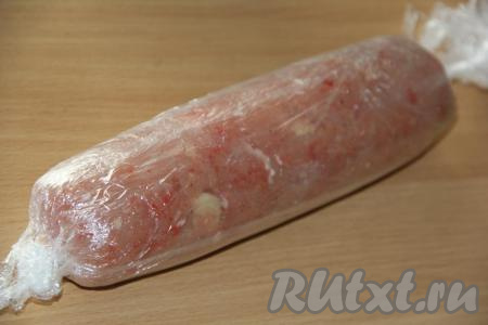 Завернуть фарш в плёнку в виде колбаски. Плотно завернуть куриную колбасу в несколько слоёв плёнки, хорошо закрепляя края плёнки с двух сторон.