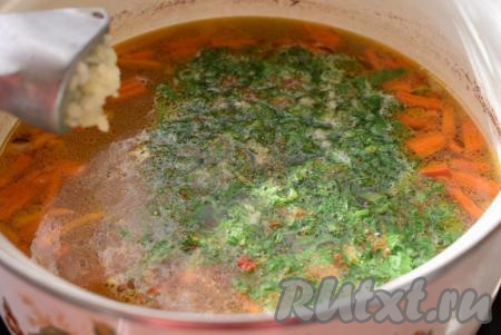 Добавляем в суп специи, колечки острого перца, выкладываем половину нарезанной зелени (оставшуюся половину зелени будем добавлять в шурпу в момент подачи в тарелку к каждому едоку). Добавляем к шурпе пропущенный через пресс чеснок,&nbsp;даём супу закипеть и выключаем огонь.