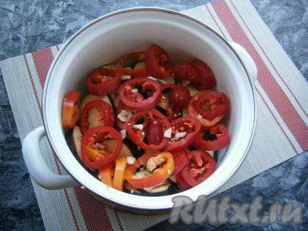 Болгарский перец, очищенный от семян, нарезать кольцами. Поверх баклажанов выложить кольца болгарского перца, очищенный и нарезанный кусочками чеснок.