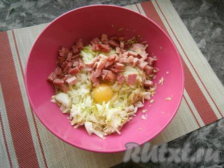Сюда же выложить колбасу, нарезанную небольшими кубиками, и сырое яйцо.